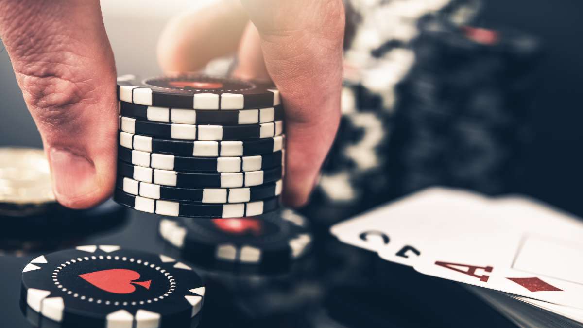 Representação de um jogo de poker com uma mão segurando as fichas e as cartas